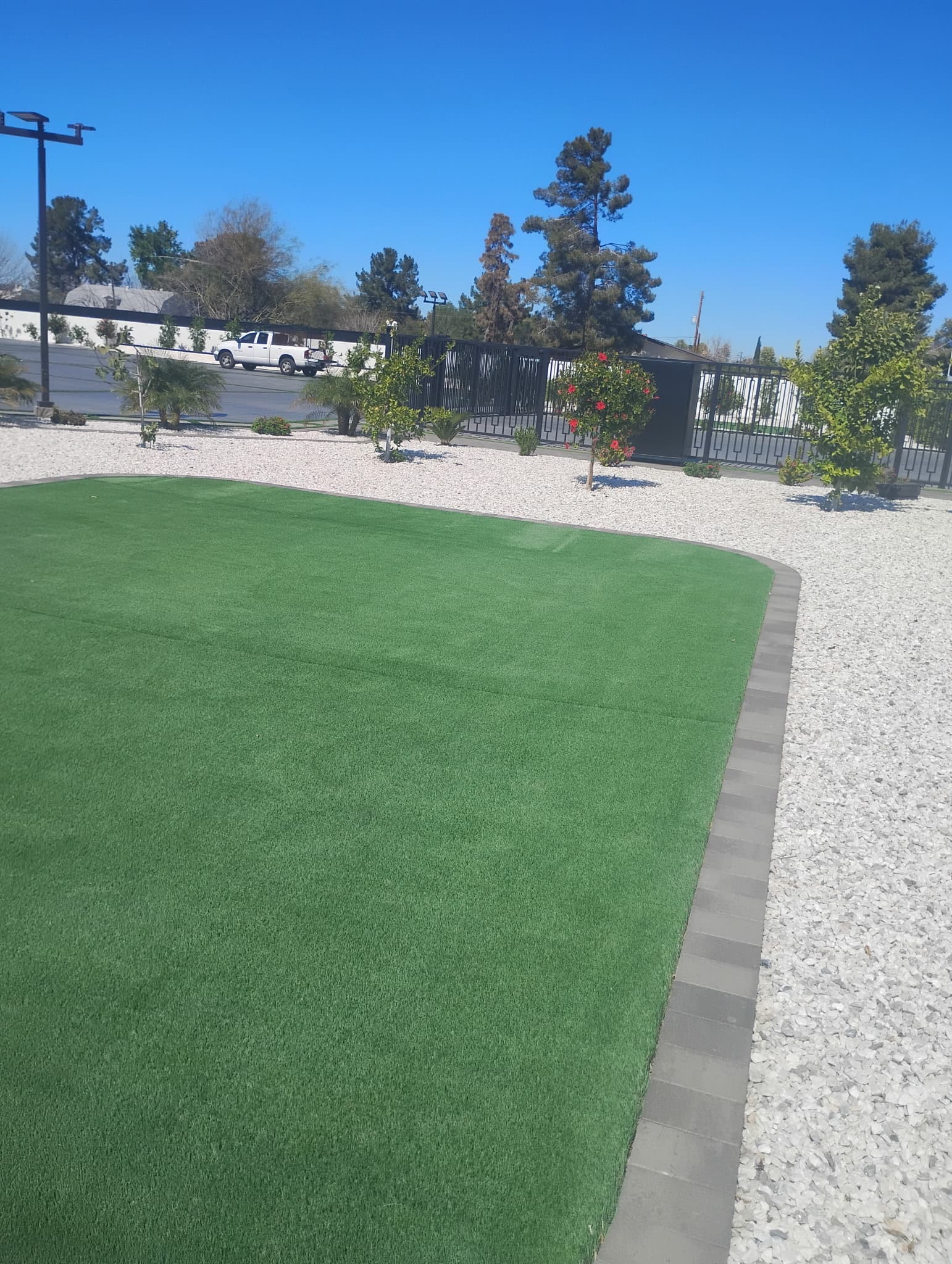 Driveway gate area with artificial turf and white rock landscape border