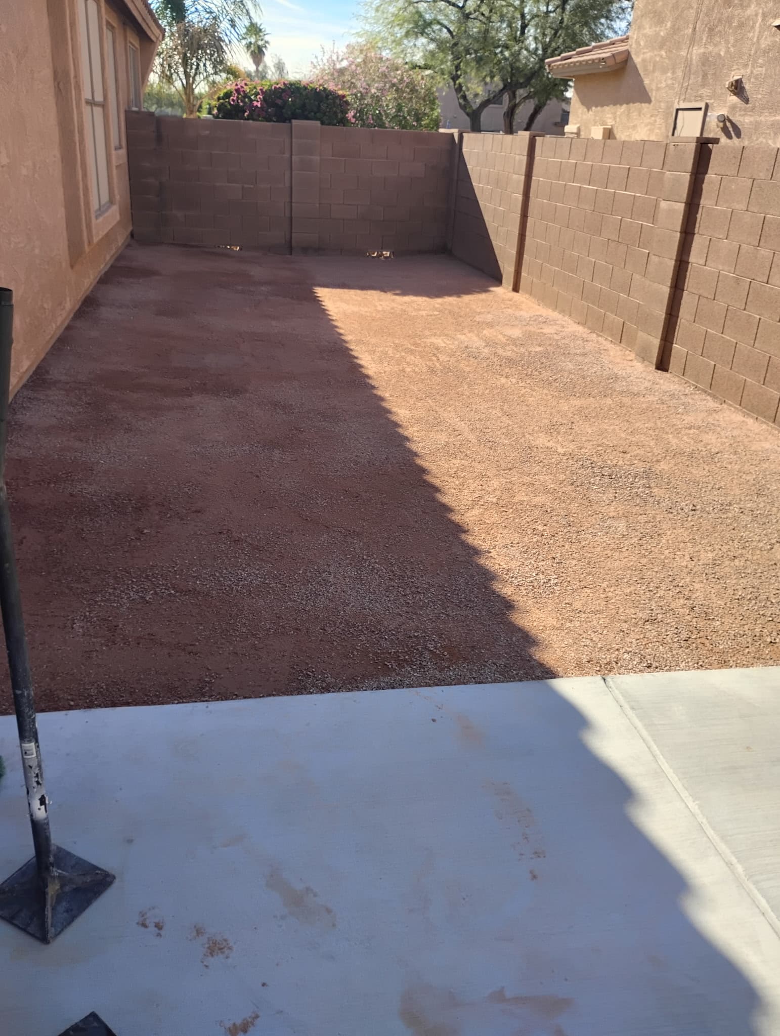 Side yard before turf installation with prepared gravel base